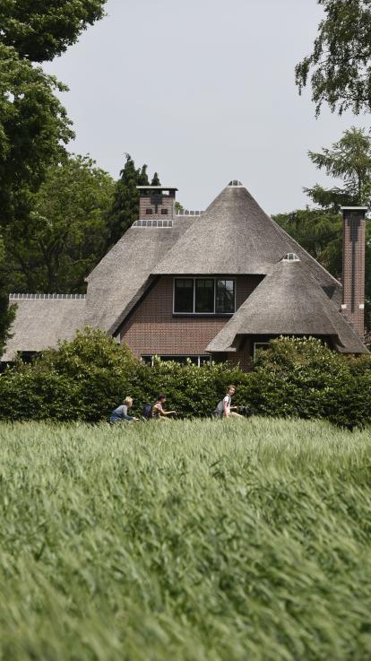 Kinderen fietsen langs een villa in 't Gooi