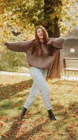 Vrouw maakt dansbeweging voor boom met herfstbladeren