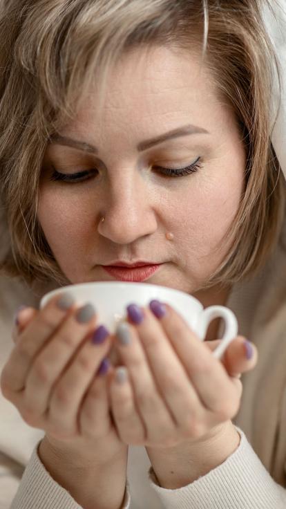iemand drinkt thee met een dekentje over zichzelf heen