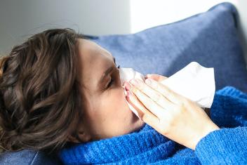 een vrouw met dikke trui niest in een zakdoekje