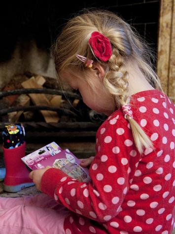 Meisje pakt cadeau uit dat ze met sint in haar schoen heeft gekregen zittend naast de open haard 