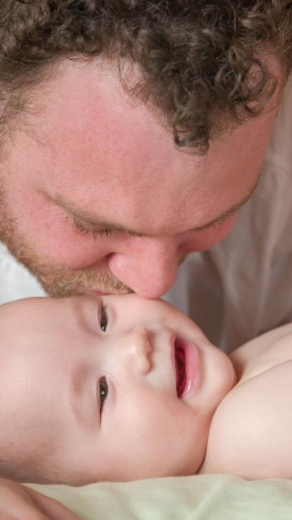 Een vader kust zijn baby op zijn wang