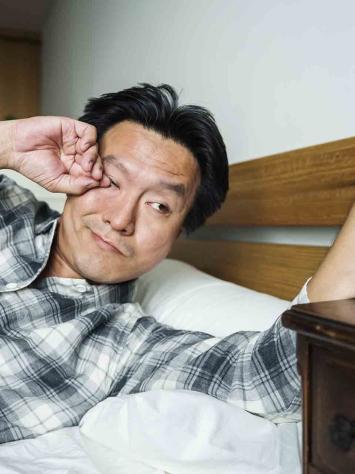 Man wordt wakker en wrijft vermoeid in zijn ogen