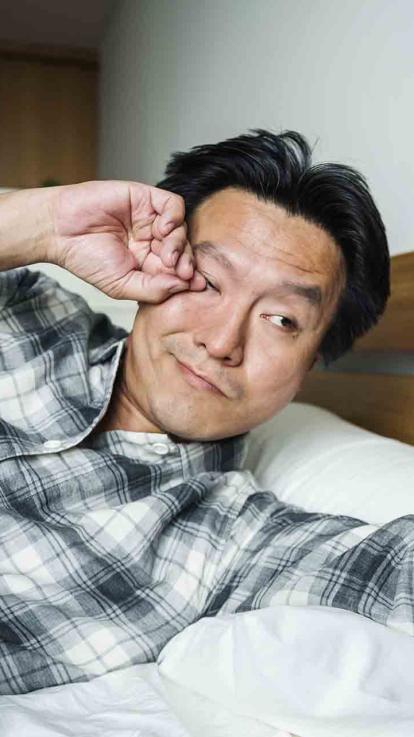 Man wordt wakker en wrijft vermoeid in zijn ogen