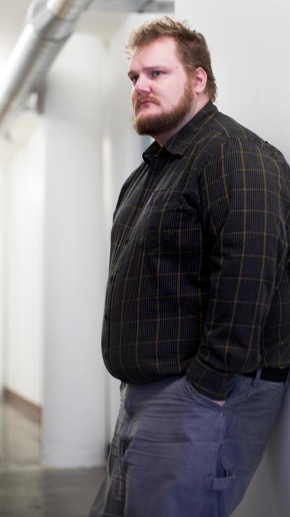 man met obesitas leunt tegen muur