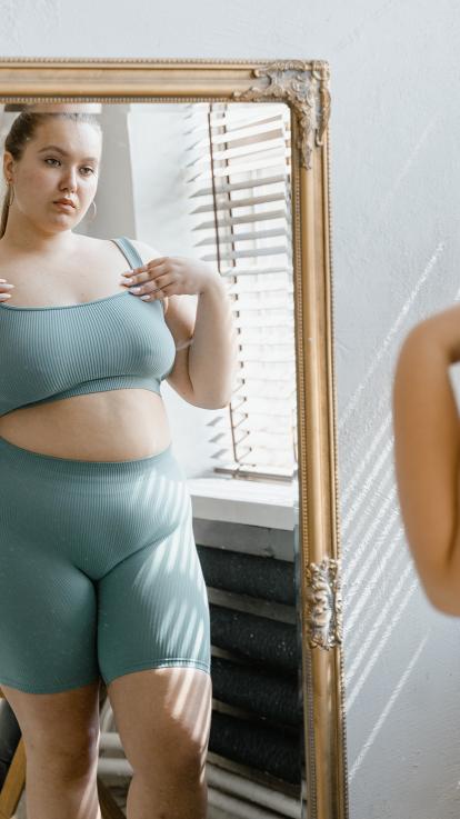 vrouw met obesitas kijkt in spiegel