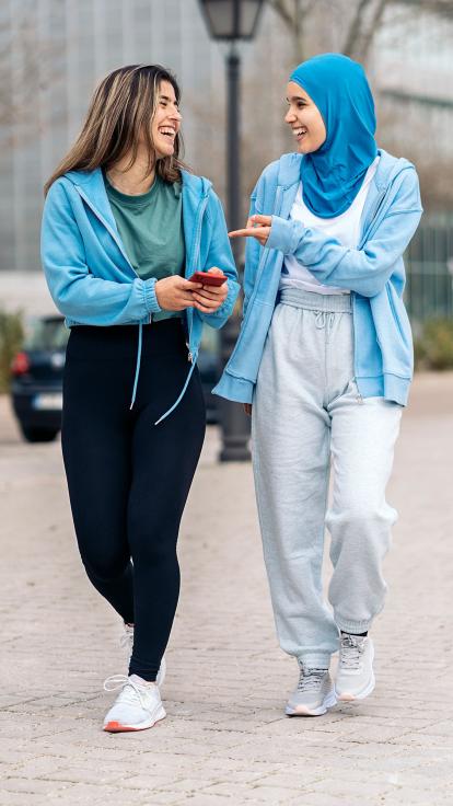 twee vrouwen lopen samen over straat, eentje met en de ander zonder hoofddoek