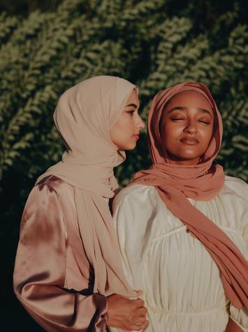 vrouwen poseren voor struik met hoofddoek om 