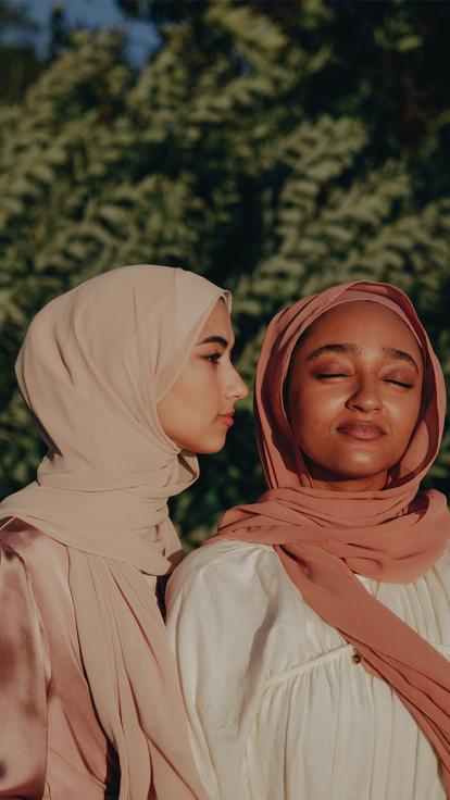 vrouwen poseren voor struik met hoofddoek om 
