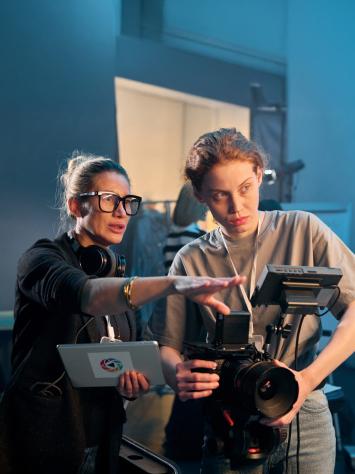 Vrouwelijke filmregisseur geeft in een studio tips aan een cameravrouw