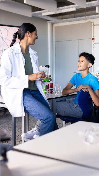 Een scheikundedocent praat met een van haar leerlingen 