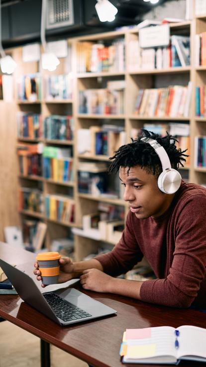 een student zit in de bibliotheek achter zijn laptop te werken