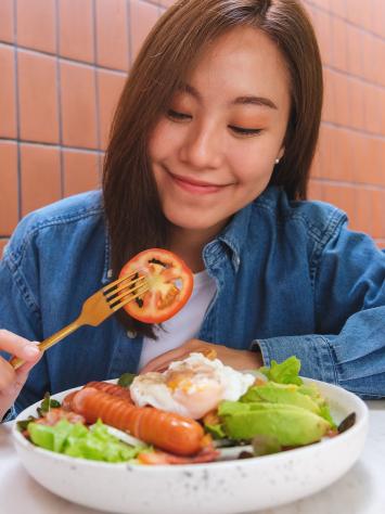een vrouw eet een maaltijd en kijkt naar een tomaat aan haar vork