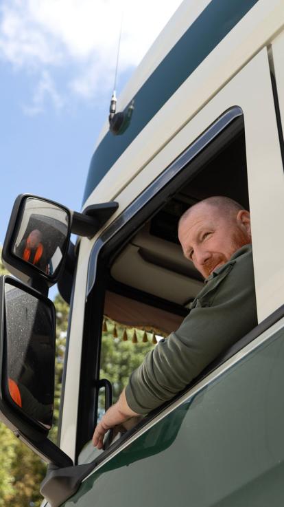 Vrachtwagenchauffeur zit in zijn wagen.