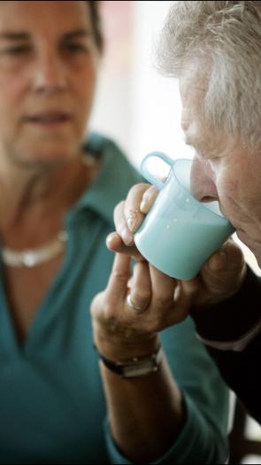 mantelzorger helpt haar oude moeder met drinken
