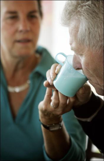 mantelzorger helpt haar oude moeder met drinken