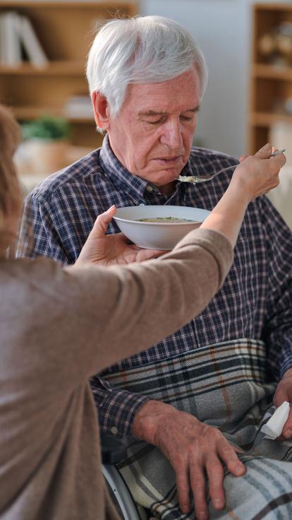 Mantelzorger geeft eten aan oudere