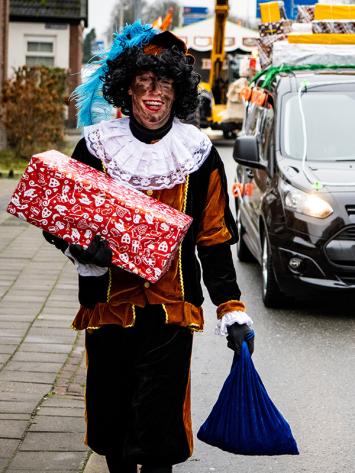 Twee pieten van sinterklaas met roetvegen op hun gezicht en pakjes in hun hand