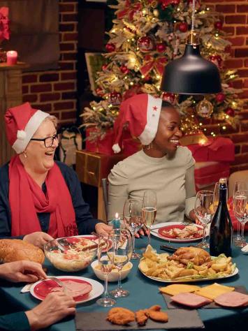 Een gezin dineert aan tafel met kerstmutsen op. 