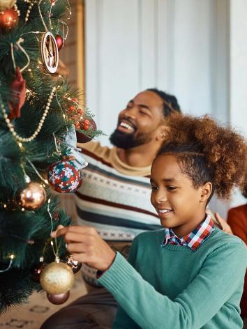 Vader en zoon tuigen een kerstboom op. 