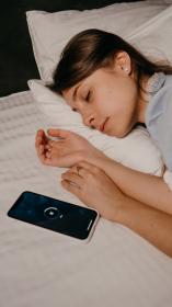 in bed naast een telefoon waar de snooze tijd afloopt
