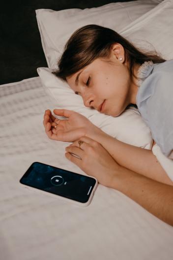 in bed naast een telefoon waar de snooze tijd afloopt