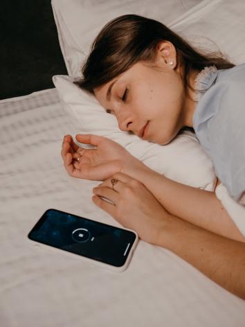 in bed naast een telefoon waar de snooze tijd afloopt