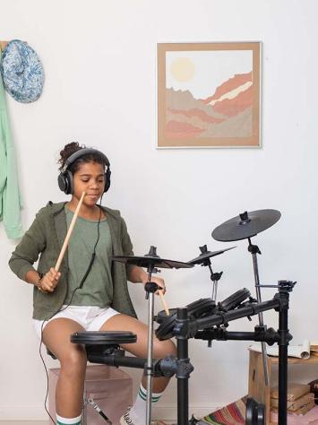 een meisje aan het drummen op haar elektrische drumstel