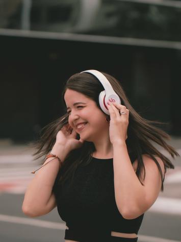 iemand luistert op straat naar muziek uit diens koptelefoon en swingt vrolijk mee