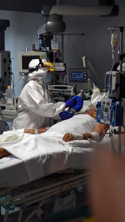 Verpleegkundige in beschermende kleding voert een behandeling uit in een kamer vol apparatuur