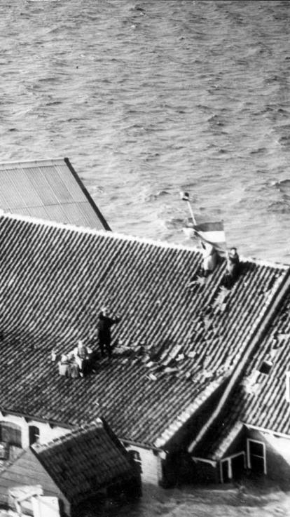 mensen op het dak van een huis dat onder water staat