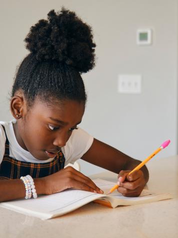 een meisje schrijft in een schrift aan tafel