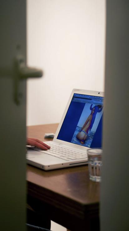 door de deur zien we iemand op beeldscherm naar porno kijken