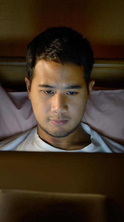 iemand kijkt achter zijn computer naar pornografie