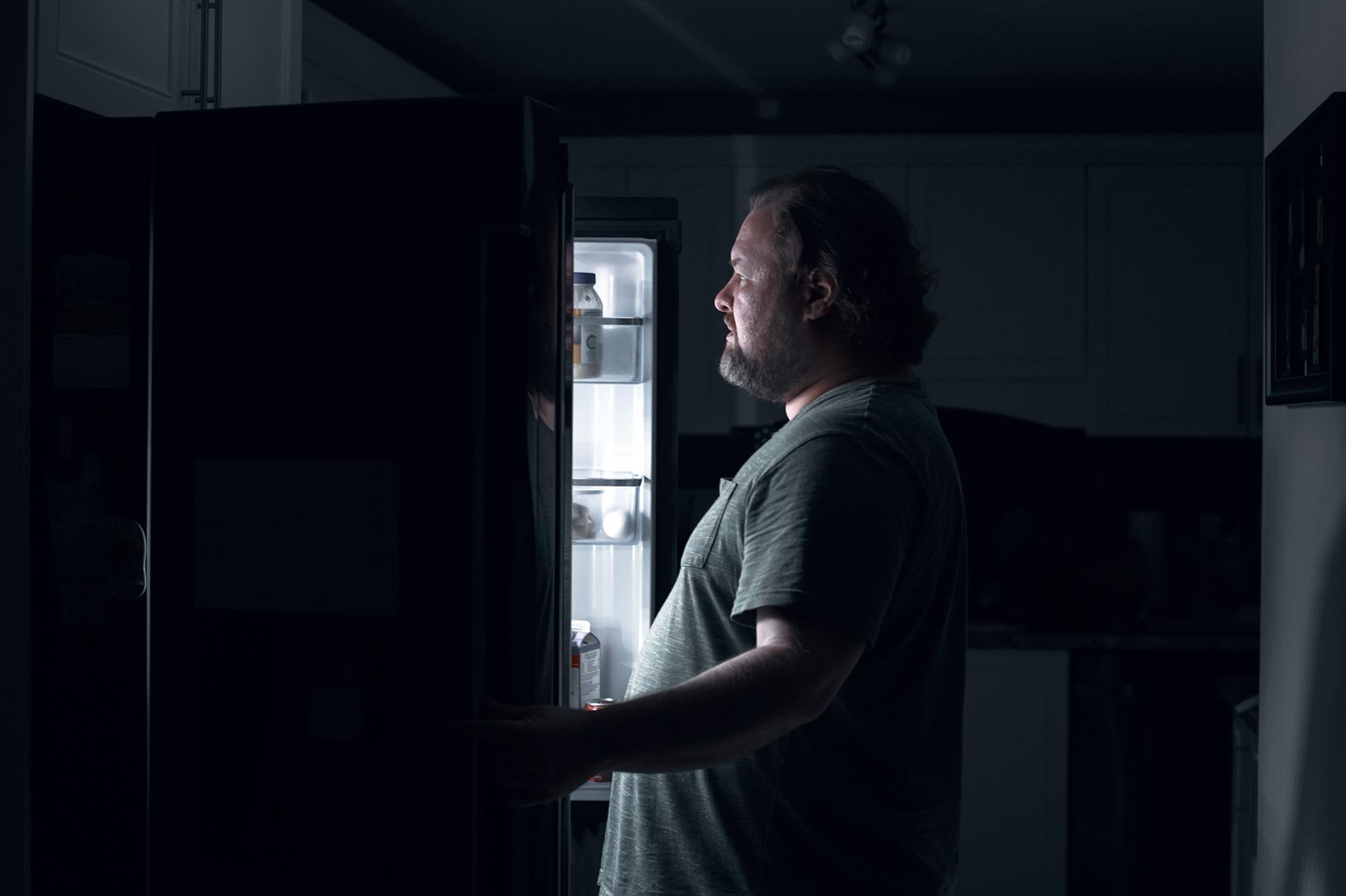 een man kijkt in de koelkast