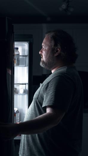 een man kijkt in de koelkast