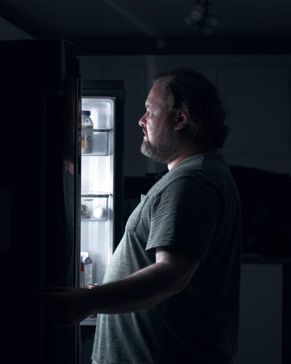 een man kijkt in de koelkast