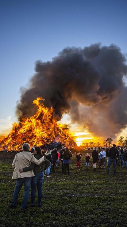 mensen kijken naar een paasvuur in Dijkerhoek