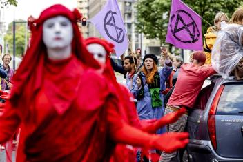 Iemand van extinction rebellion houdt een vuist in de lucht. 