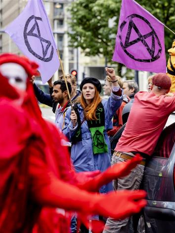 Iemand van extinction rebellion houdt een vuist in de lucht.