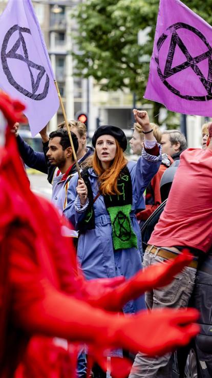 Iemand van extinction rebellion houdt een vuist in de lucht. 