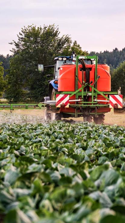 een trekker sproeit pesticiden over de gewassen