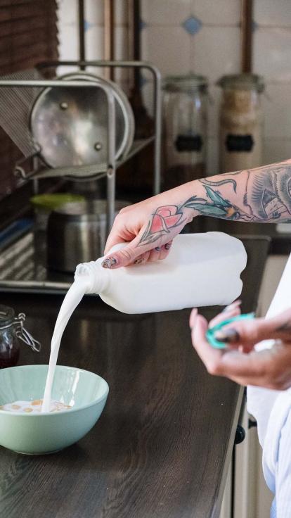 iemand schenkt melk in een kom met cornflakes