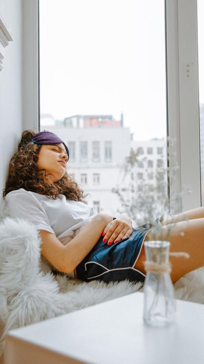 Een meisje heeft last van haar ongesteldheid en aait met haar handen over haar buik. 