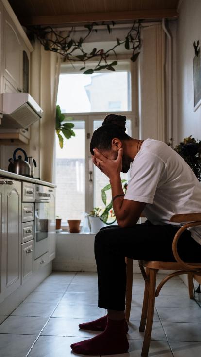 iemand zit depressief op stoel in de keuken