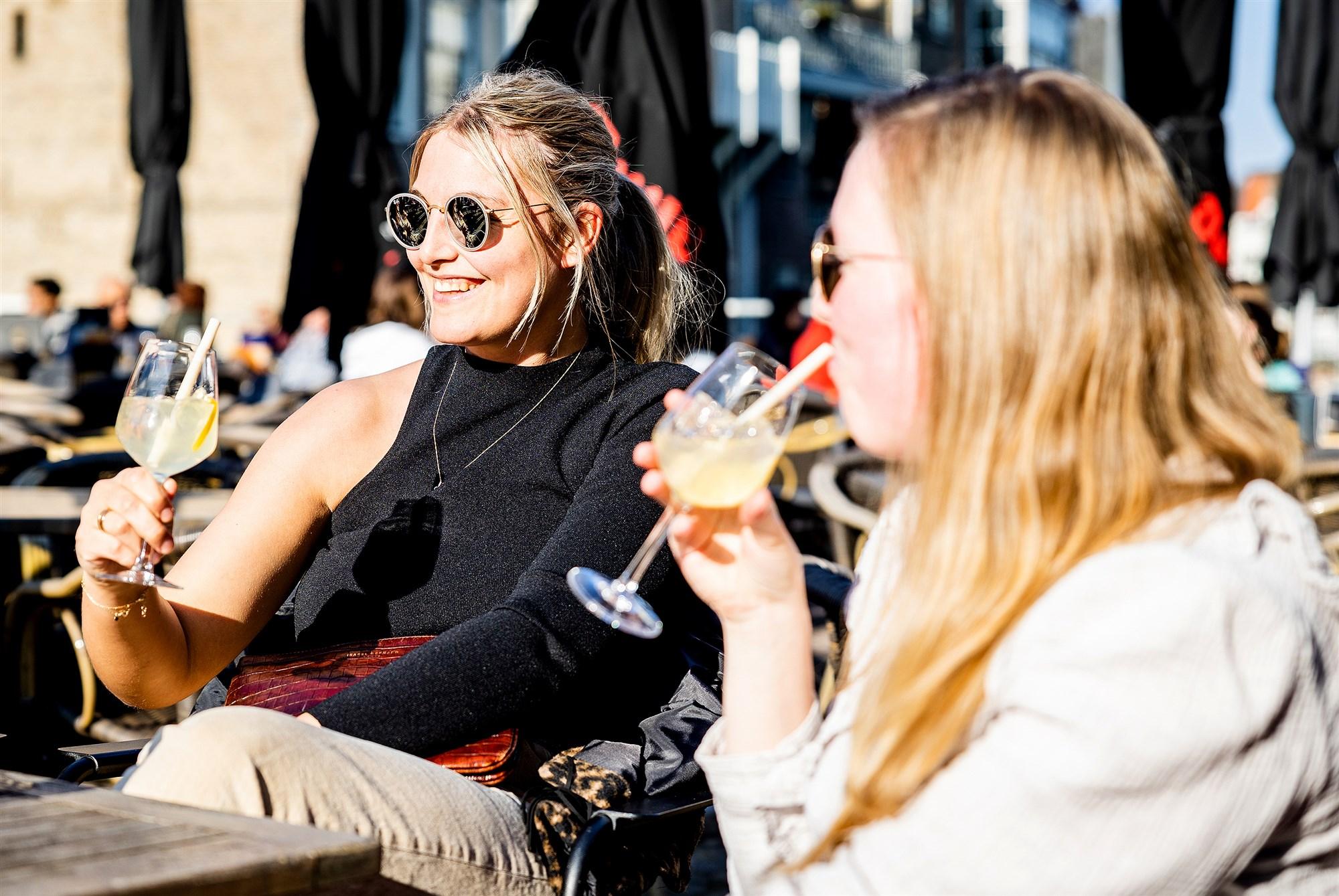 Twee vrouwen drinken een drankje op een terras in de zon