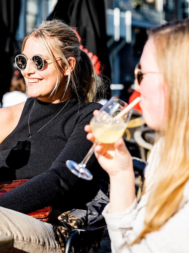 Twee vrouwen drinken een drankje op een terras in de zon