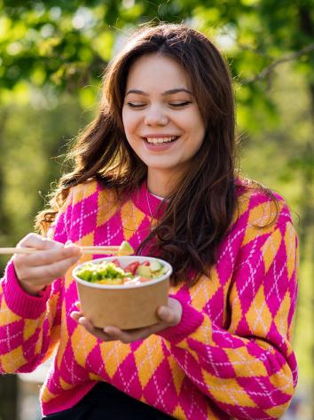 iemand eet groenten van een poké bowl