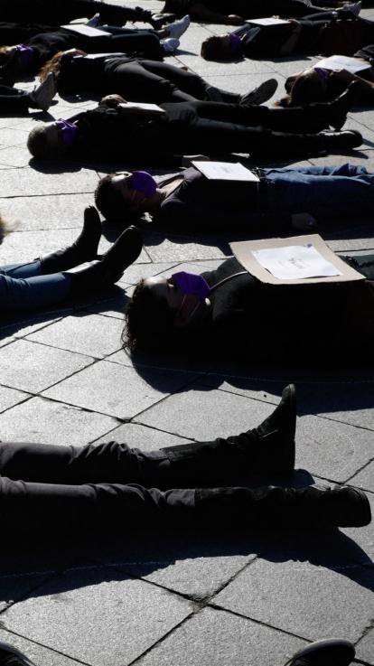 vrouwen liggen op de grond bij een protest tegen femicide