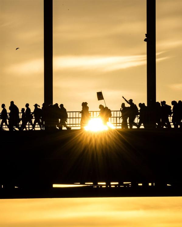 wandelaars bij zonsopkomst op de brug